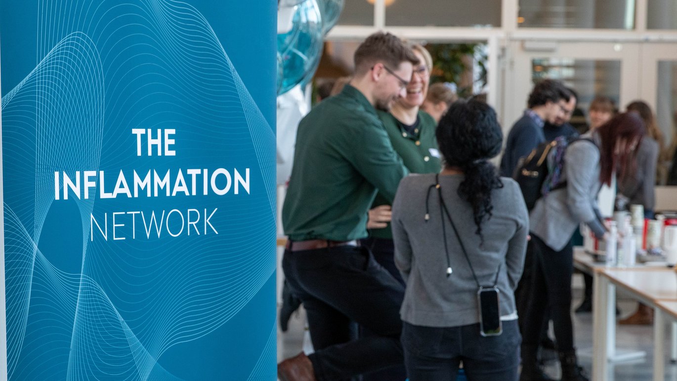 The photo shows a sign saying the Inflammation Network. Happy people are standing in the background.