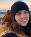 Billedet viser Mette Mørup Schlütter i et sneklædt lndskab med et lille barn i en slynge på ryggen.